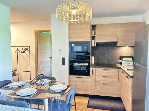 une cuisine et une salle à manger avec une table et des chaises dans l'établissement Les Gets - Appartement dans une résidence neuve - FR-1-623-4, aux Gets
