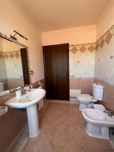 a bathroom with two sinks and a toilet and a mirror at Attico Etnamare in Gravina di Catania