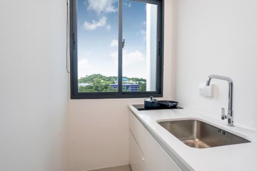 une cuisine blanche avec un évier et une fenêtre dans l'établissement New Studio with Disability-Friendly Features, Central Hill View A6-724 A, à Ban Ket Ho