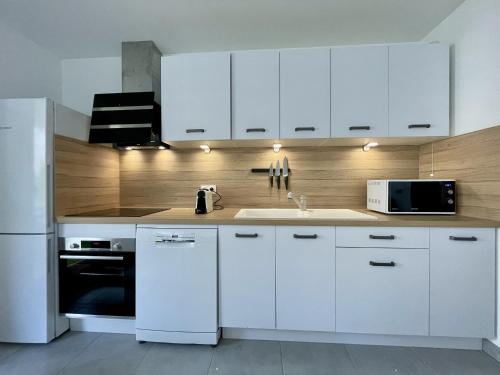 a kitchen with white cabinets and a sink at Alba in Laxou