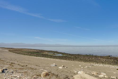 a beach with rocks and the ocean on a sunny day at Stunning Home in Coupeville with Deck and Beach Access in Coupeville
