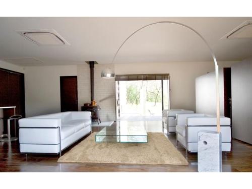 Haramura - house / Vacation STAY 2211 في Hara: غرفة معيشة بها كنبتين بيضاء وطاولة زجاجية
