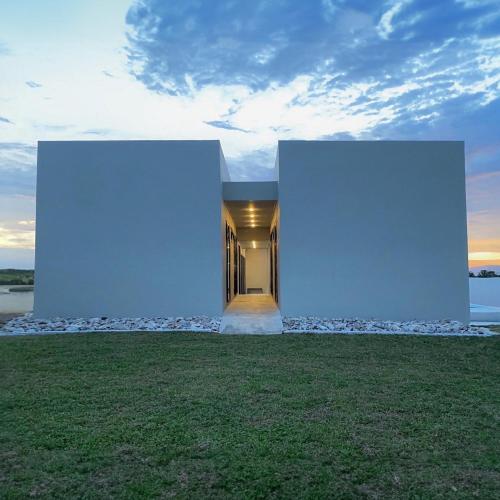 a house with two white walls on a grass field at holiday fever x the pool in Ban Sap Noi