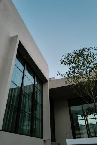 a building with windows and a tree in front of it at holiday fever x the pool in Ban Sap Noi