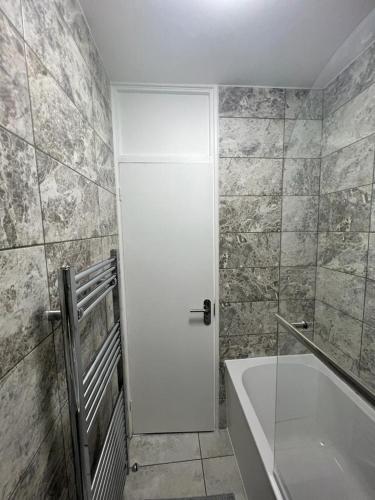 a bathroom with a white door and a bath tub at T Lodge in Abbey Wood