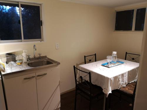 a kitchen with a sink and a table with chairs at CABAÑA LIRCAY - 2 habitaciones 48M2 para 4 personas in San Clemente
