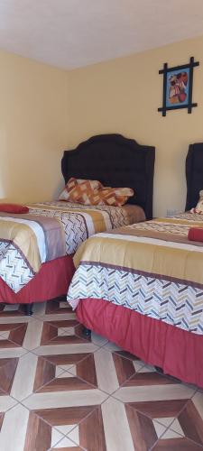 two beds sitting in a room with a floor at Hotel los reyes in Cobán