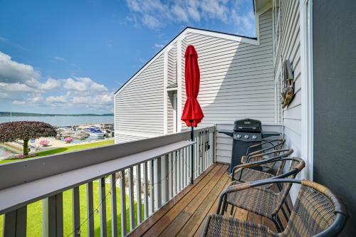 a balcony with chairs and a red umbrella at Luxury Lakefront Boyne City Townhome with Views! in Boyne City