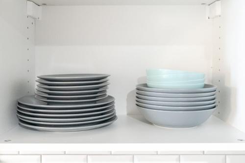 une pile de plaques et de bols dans une armoire blanche dans l'établissement Elegant cocoon 3 people - Perrache-Confluence, à Lyon