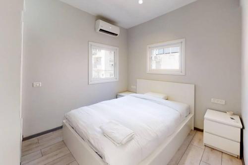 - une chambre blanche avec un lit et 2 fenêtres dans l'établissement Stunning 3BR - Ben Yehuda Gordon, à Tel Aviv