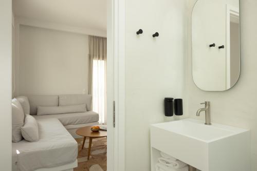 Baño blanco con lavabo y espejo en NŌSTOS Serifos, en Livadion