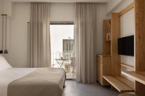 Habitación de hotel con cama y TV en NŌSTOS Serifos, en Livadion