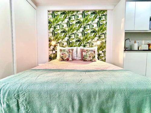 1 dormitorio con 1 cama grande con colcha verde en New-Romantic studio near the beach!, en Paço de Arcos