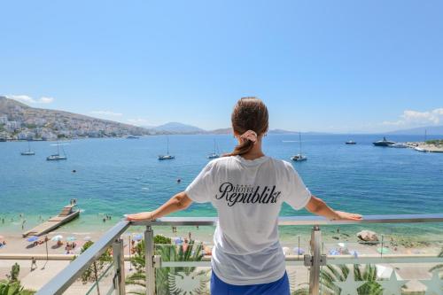 a person standing on a balcony looking at the beach at Republika Hotel in Sarandë