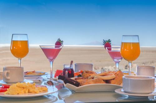 a table with a plate of food and wine glasses at Hotel de Sal Luna Salada in Colchani