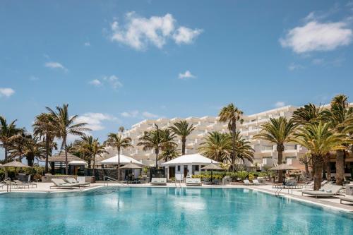 a large swimming pool with palm trees and a large building at Paradisus by Meliá Salinas Lanzarote - All Inclusive - Adults Only in Costa Teguise
