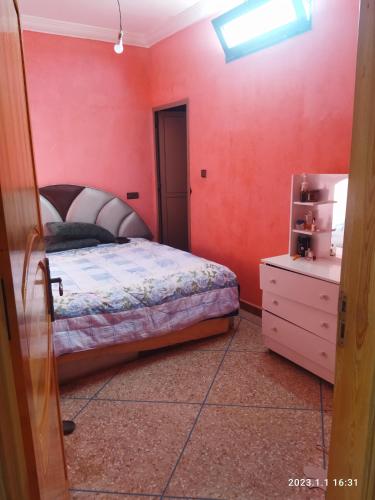 1 dormitorio con paredes rojas, 1 cama y vestidor en Villa Agadir Maroc, en Agadir