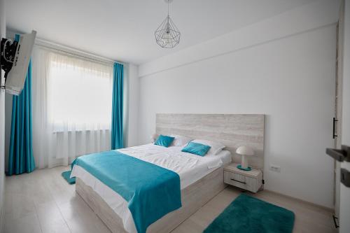 een slaapkamer met een bed met blauwe lakens en een raam bij Alessandro Home 8 Luxury Centru Palas Mall Iași Q Residence in Iaşi