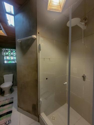 a shower with a glass door in a bathroom at Pousada Raiz Forte in Caraíva