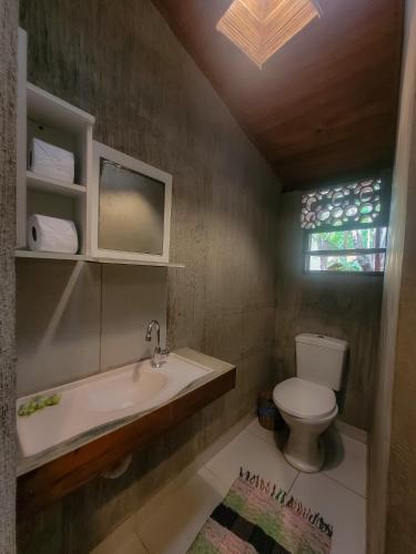a bathroom with a sink and a toilet and a window at Pousada Raiz Forte in Caraíva