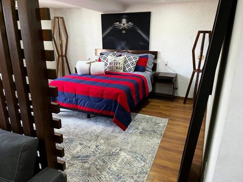Schlafzimmer mit einem Bett mit einer roten und blauen Decke in der Unterkunft Madre tierra suites tlalpujahua centro in Tlalpujahua