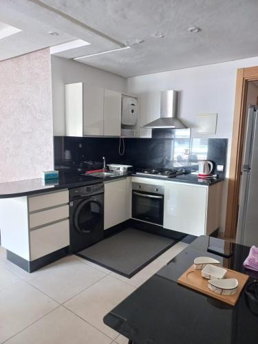 uma cozinha com electrodomésticos a preto e branco e uma mesa em appartement luxe em Mohammedia