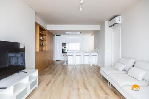 een woonkamer met een witte bank en een keuken bij Malibu by Cadiz Time in Cádiz