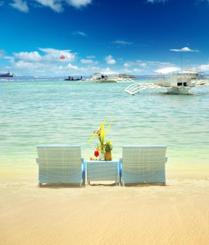 two chairs and a table on the beach at Cebu White Sands Resort and Spa in Mactan