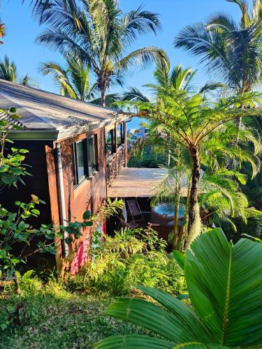 a small house with a wooden porch in a garden at OHANA Jungle Lodges in Les Avirons