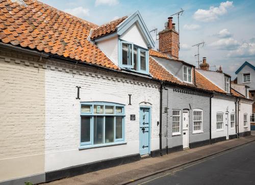 a white building with a blue door on a street at 7 Church Street, Southwold in Southwold