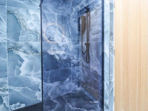 a shower in a bathroom with blue tiles at Cottage by the River in Burnley