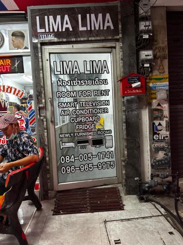 a woman sitting in a chair in front of a store door at Hotel lima lima in Pattaya
