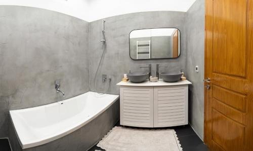 bagno con vasca, lavandino e specchio di Luminous Luxury Apartment a Chania