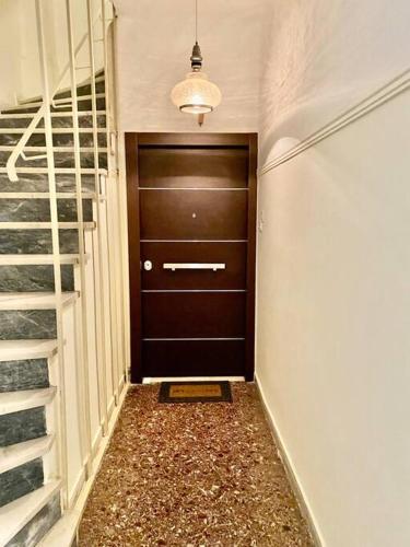 een hal met een bruine deur en een trap bij Lovely flat Korydallos in Piraeus