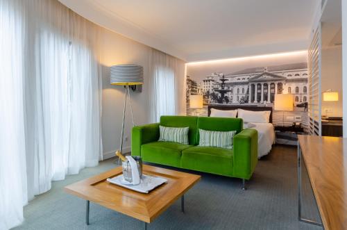 uma sala de estar com um sofá verde e uma cama em Olissippo Saldanha em Lisboa