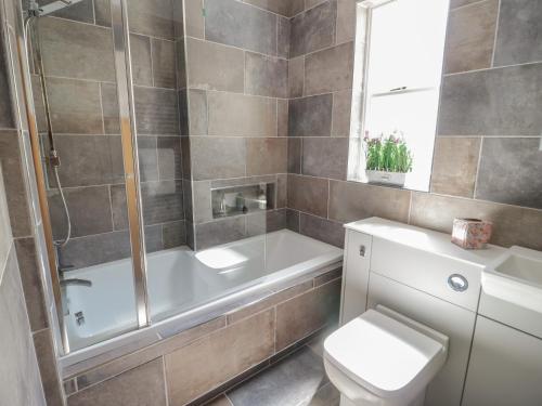 a bathroom with a tub and a toilet and a sink at The Moorings in Deganwy