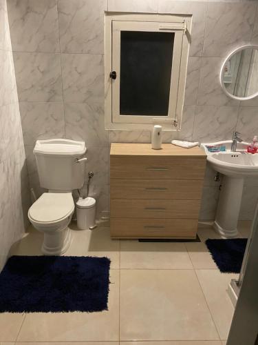 bagno con servizi igienici, lavandino e specchio di The Cottage a Luqa