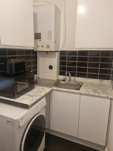 uma cozinha com um lavatório e uma máquina de lavar roupa em Manhattan Studio flat northbridge services em Londres