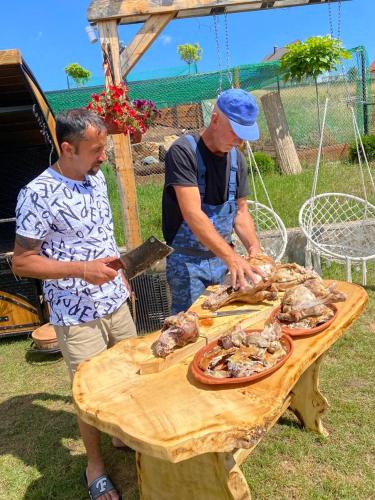 two men standing around a table with food on it at Vila Deniri in Zlatibor
