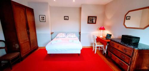 a bedroom with a bed and a desk and a red rug at Le Sequoia in Velles
