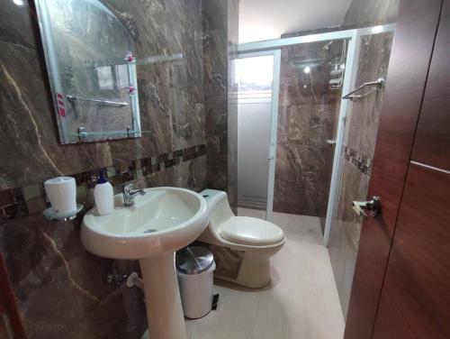 La salle de bains est pourvue d'un lavabo, de toilettes et d'une douche. dans l'établissement Hospedaje Charlie's House, à Baños