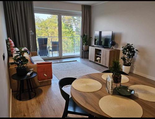 a living room with a table and a television at Apartamenty hotelowe w Jarosławcu in Jarosławiec