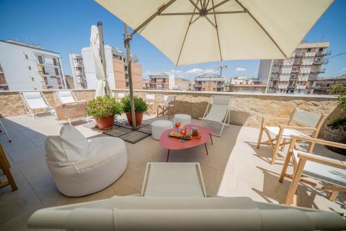 a patio with a table and chairs and an umbrella at Palazzo Fontana B&B e SPA in Gravina in Puglia