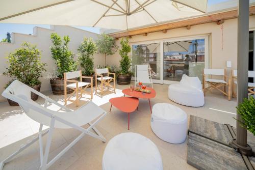 a patio with chairs and tables and an umbrella at Palazzo Fontana B&B e SPA in Gravina in Puglia