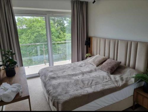 a bedroom with a bed and a large window at Apartamenty hotelowe w Jarosławcu in Jarosławiec