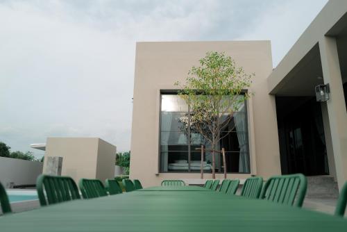 a room with chairs and a table and a tree at holiday fever x the pool in Ban Sap Noi