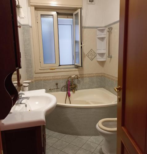 a bathroom with a tub and a sink and a toilet at Alba Marina e Tramonti Etnei in Riposto