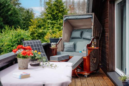 um alpendre com uma cadeira e uma mesa com flores em Feriendomizil Tippe em Braunlage