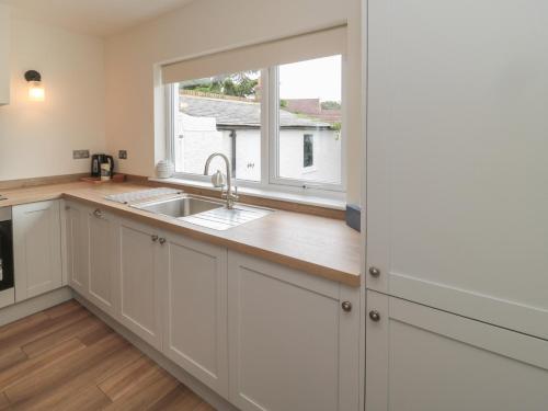 a kitchen with a sink and a window at Gudhjem in Seahouses