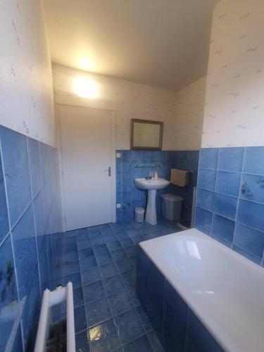 La salle de bains est pourvue de carrelage bleu, d'une baignoire et d'un lavabo. dans l'établissement Beatitude62, à Fauquembergues